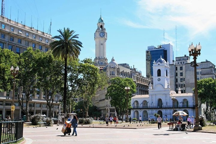 a group of people walking down a street next to a clock tower